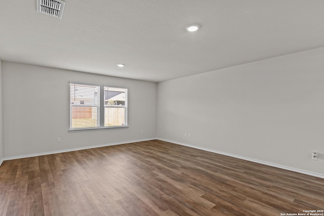 empty room with recessed lighting, dark wood finished floors, visible vents, and baseboards