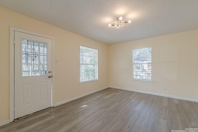 entrance foyer featuring a textured ceiling, wood finished floors, and baseboards