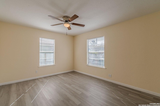 spare room featuring ceiling fan, baseboards, and wood finished floors