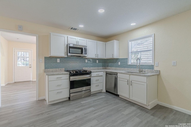 kitchen featuring stainless steel appliances, visible vents, a sink, and tasteful backsplash