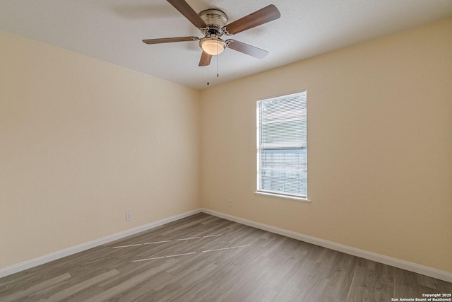 unfurnished room with a ceiling fan, baseboards, and wood finished floors