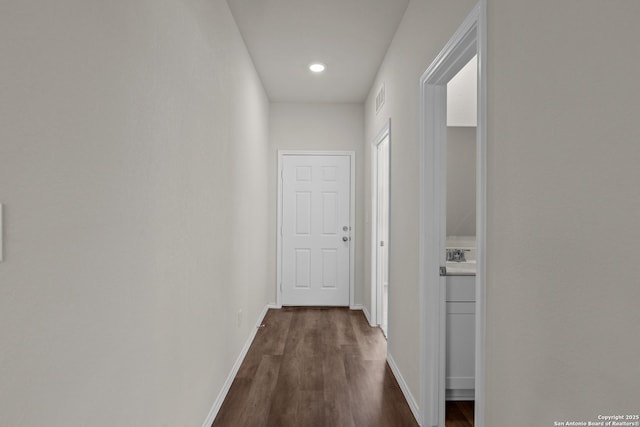 corridor with dark wood-style floors, visible vents, and baseboards