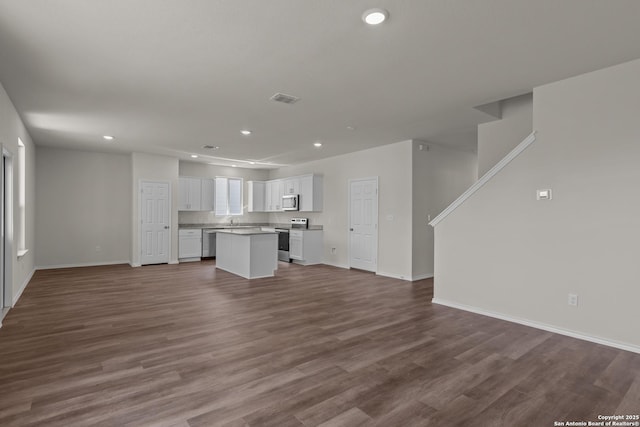 unfurnished living room featuring dark wood-style flooring and recessed lighting