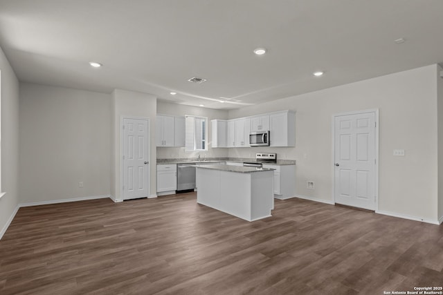 kitchen with recessed lighting, stainless steel appliances, white cabinets, a center island, and dark wood finished floors