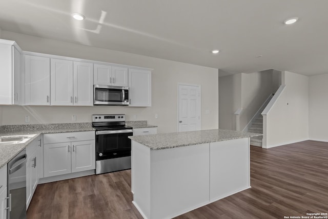 kitchen featuring stainless steel appliances, a center island, white cabinetry, and dark wood finished floors