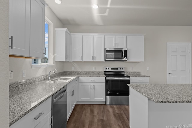 kitchen with stainless steel appliances, dark wood finished floors, white cabinetry, and a sink