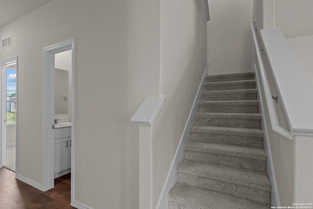 stairs with wood finished floors, visible vents, and baseboards