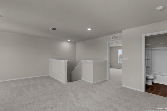 carpeted spare room featuring baseboards, visible vents, and recessed lighting