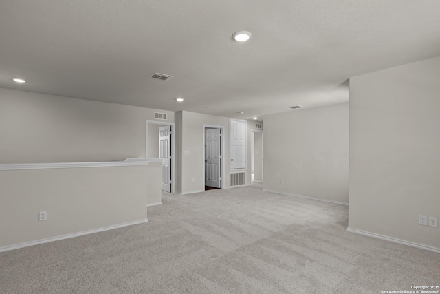 carpeted spare room featuring baseboards, visible vents, and recessed lighting