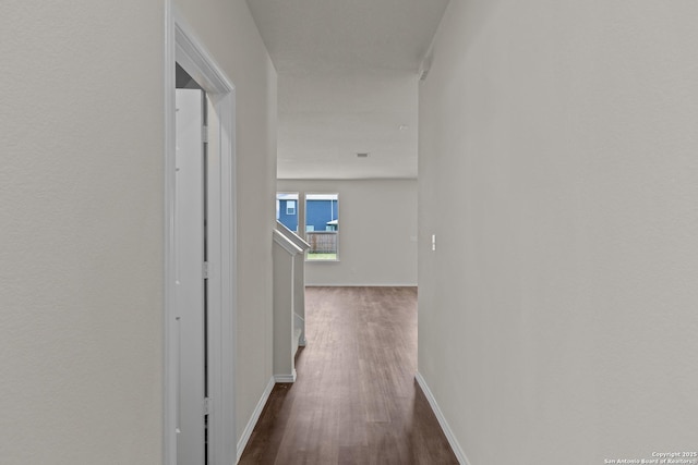 corridor with baseboards and dark wood-type flooring