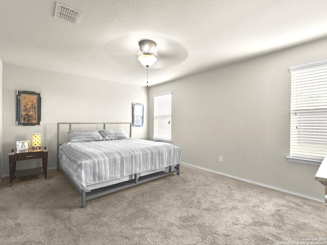 carpeted bedroom featuring a textured ceiling, a ceiling fan, visible vents, and baseboards