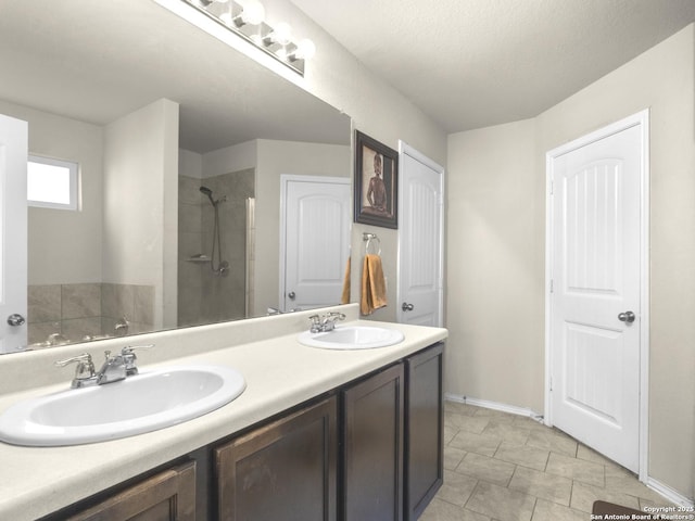 bathroom with tile patterned flooring, tiled shower, a sink, and double vanity