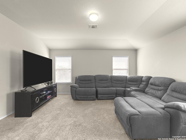 carpeted living room with a healthy amount of sunlight, vaulted ceiling, visible vents, and baseboards