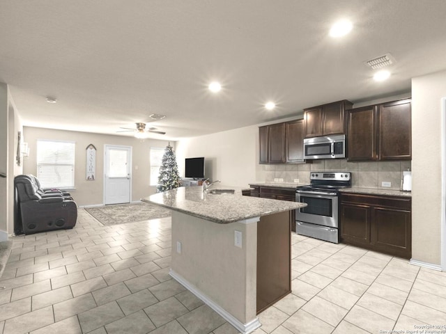 kitchen with appliances with stainless steel finishes, open floor plan, a sink, and light tile patterned floors