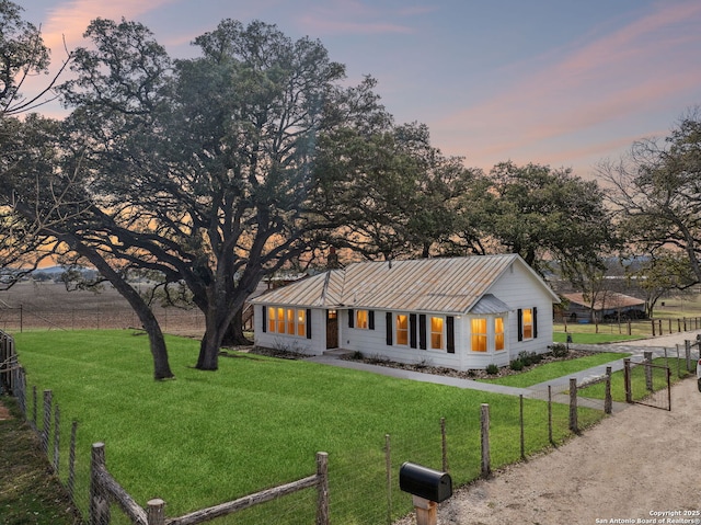 view of front facade featuring a standing seam roof, fence, metal roof, and a front yard