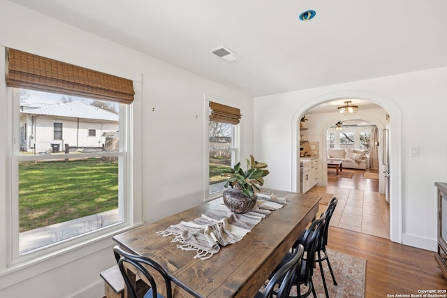 dining room with arched walkways, visible vents, and wood finished floors