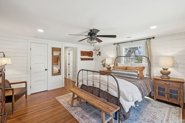 bedroom with wood walls, wood finished floors, visible vents, and recessed lighting