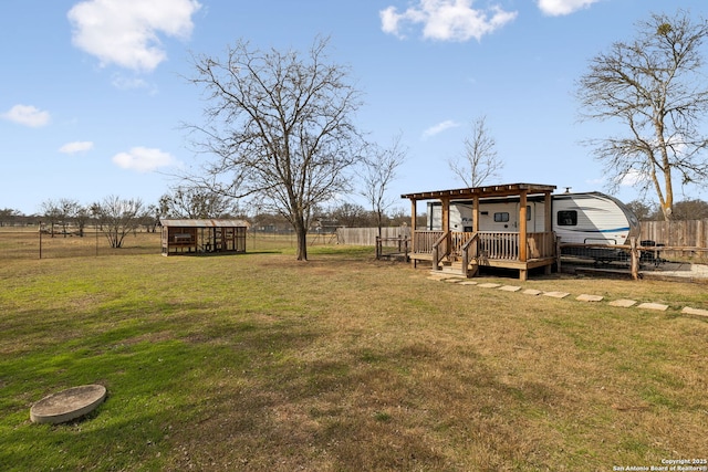 view of yard featuring fence, a wooden deck, and an outdoor structure