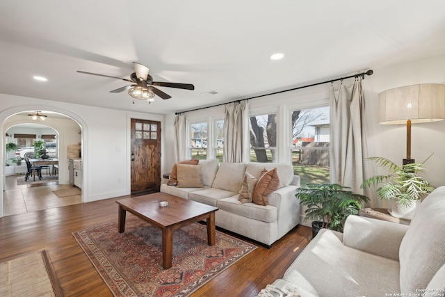 living room featuring a ceiling fan, arched walkways, plenty of natural light, and wood finished floors