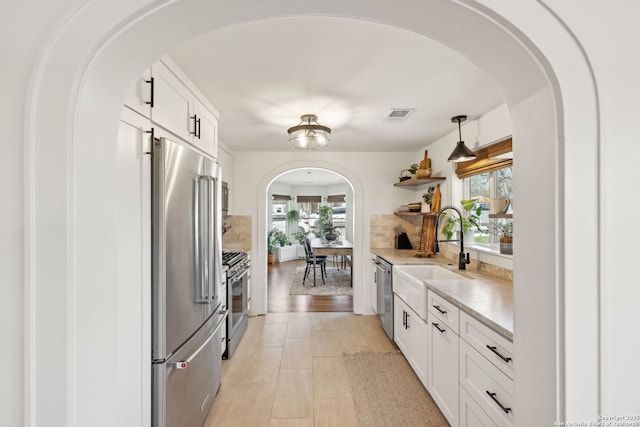 kitchen featuring open shelves, visible vents, appliances with stainless steel finishes, white cabinetry, and a sink