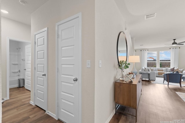 hallway featuring dark wood-style floors, visible vents, and baseboards