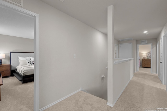 corridor with carpet, visible vents, baseboards, and an upstairs landing