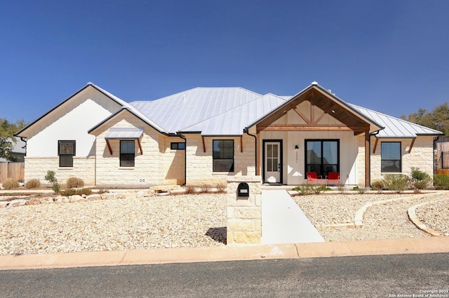 modern inspired farmhouse with metal roof, stone siding, and a standing seam roof