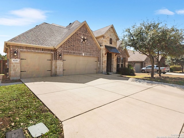 view of front of house featuring roof with shingles, brick siding, concrete driveway, an attached garage, and stone siding