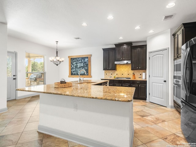 kitchen featuring visible vents, a sink, tasteful backsplash, appliances with stainless steel finishes, and a large island with sink