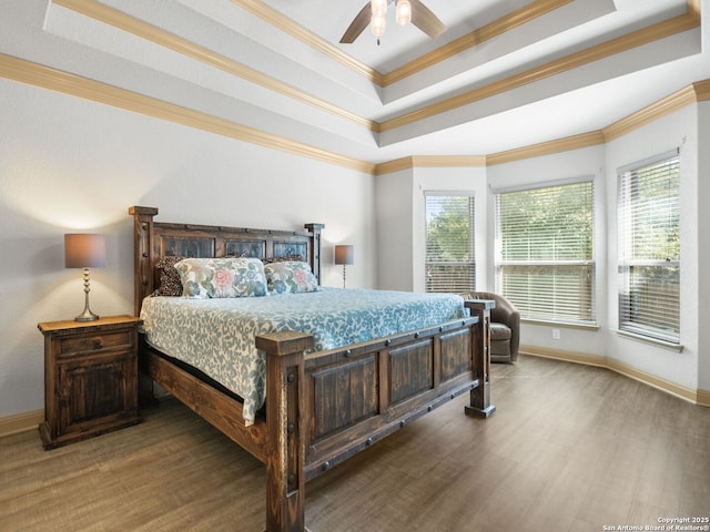 bedroom with a tray ceiling, wood finished floors, and ornamental molding