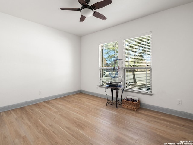 empty room featuring light wood-type flooring, baseboards, and a ceiling fan