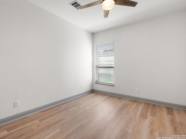 spare room with visible vents, light wood-style flooring, baseboards, and ceiling fan