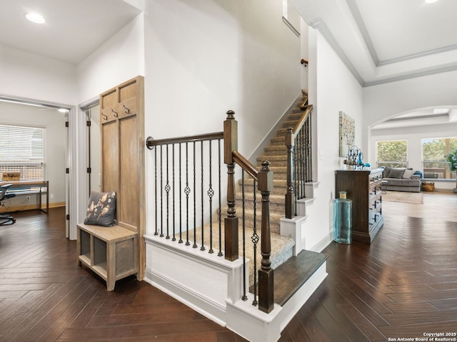 staircase featuring baseboards, recessed lighting, arched walkways, ornamental molding, and parquet flooring