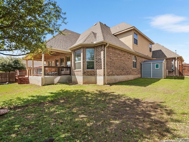 rear view of house featuring a yard, an outbuilding, brick siding, and fence