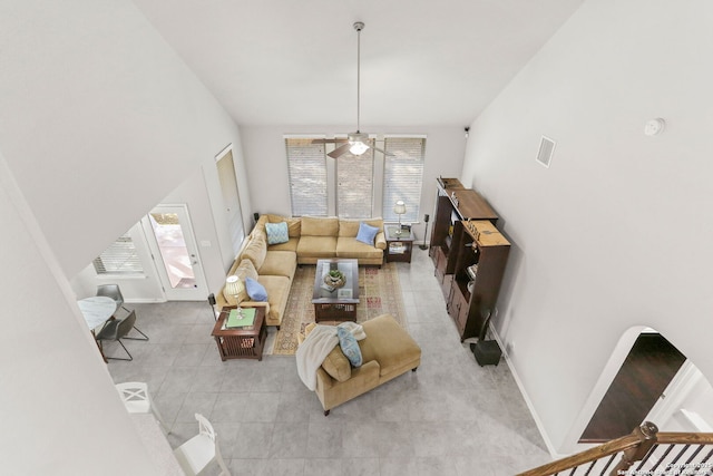 living area with ceiling fan, light tile patterned floors, a wealth of natural light, and baseboards