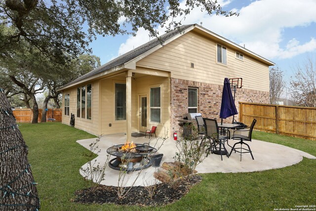 back of house with an outdoor fire pit, a fenced backyard, a yard, and a patio