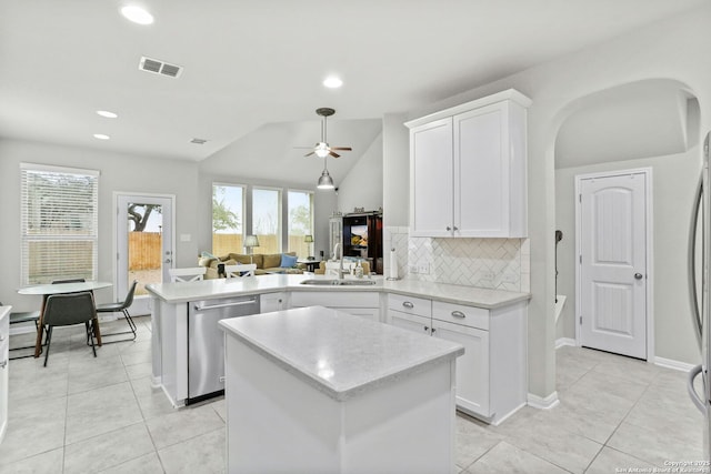 kitchen featuring visible vents, backsplash, stainless steel dishwasher, a sink, and a peninsula