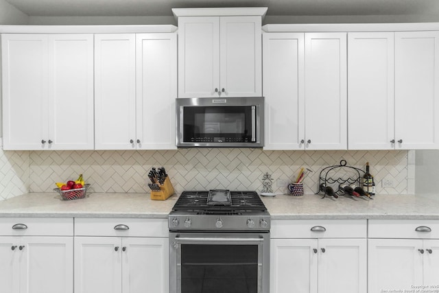 kitchen with appliances with stainless steel finishes, white cabinetry, backsplash, and light stone countertops