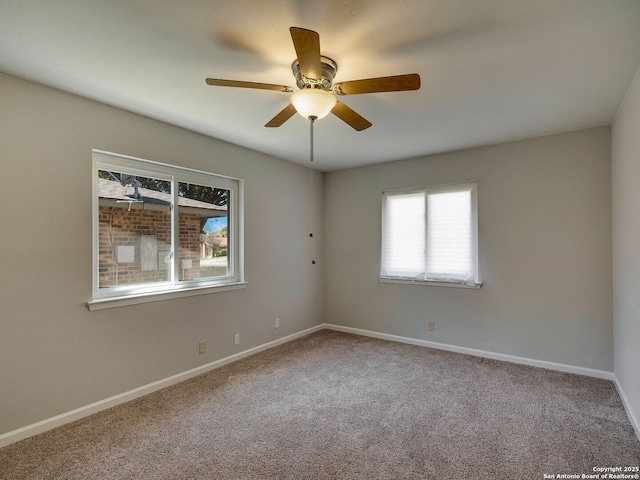 carpeted empty room featuring ceiling fan and baseboards