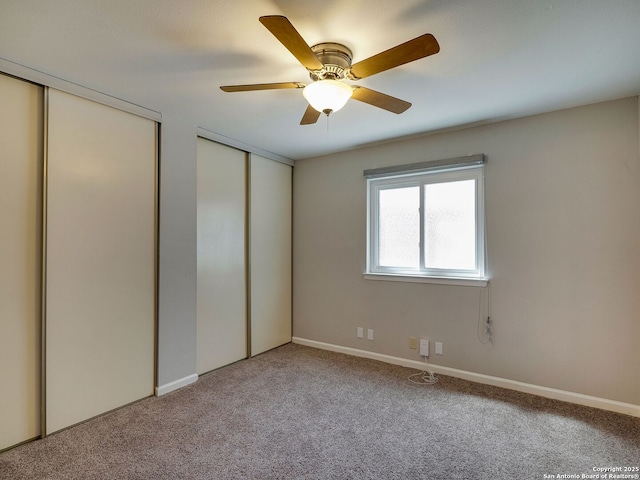 unfurnished bedroom with ceiling fan, multiple closets, and light colored carpet