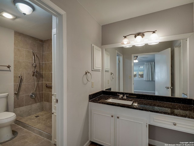 full bathroom featuring ceiling fan, toilet, vanity, a tile shower, and tile patterned floors