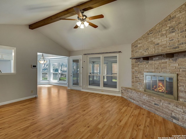 unfurnished living room featuring baseboards, a ceiling fan, lofted ceiling with beams, light wood-style flooring, and a brick fireplace