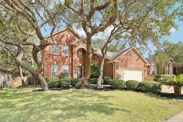 traditional-style house with a garage, a front yard, fence, and brick siding