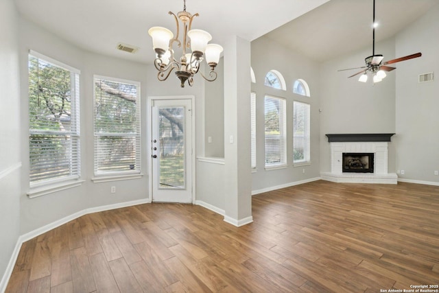 interior space with a brick fireplace, wood finished floors, visible vents, and a healthy amount of sunlight