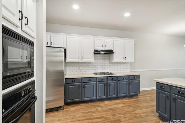 kitchen featuring gray cabinetry, light wood-style floors, white cabinets, under cabinet range hood, and black appliances