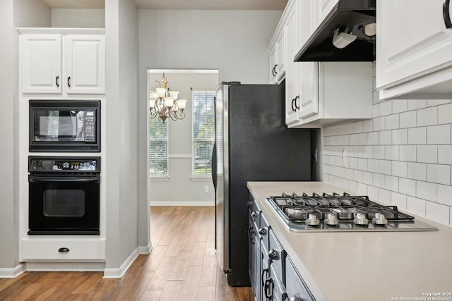 kitchen featuring black appliances, under cabinet range hood, white cabinetry, and decorative backsplash