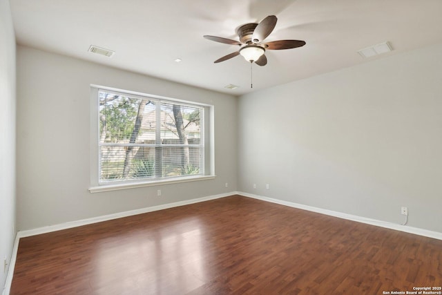 empty room featuring dark wood-style floors, visible vents, and baseboards