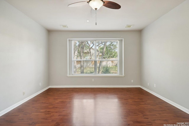 empty room featuring visible vents, wood finished floors, a ceiling fan, and baseboards