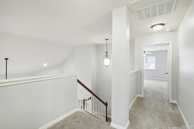 hallway featuring baseboards, visible vents, vaulted ceiling, carpet flooring, and an upstairs landing