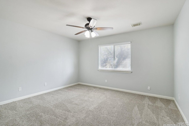 carpeted spare room featuring baseboards, visible vents, and a ceiling fan